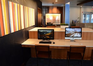 A reception desk with two monitors, a keyboard, and a mouse. There are two chairs in front of the desk.