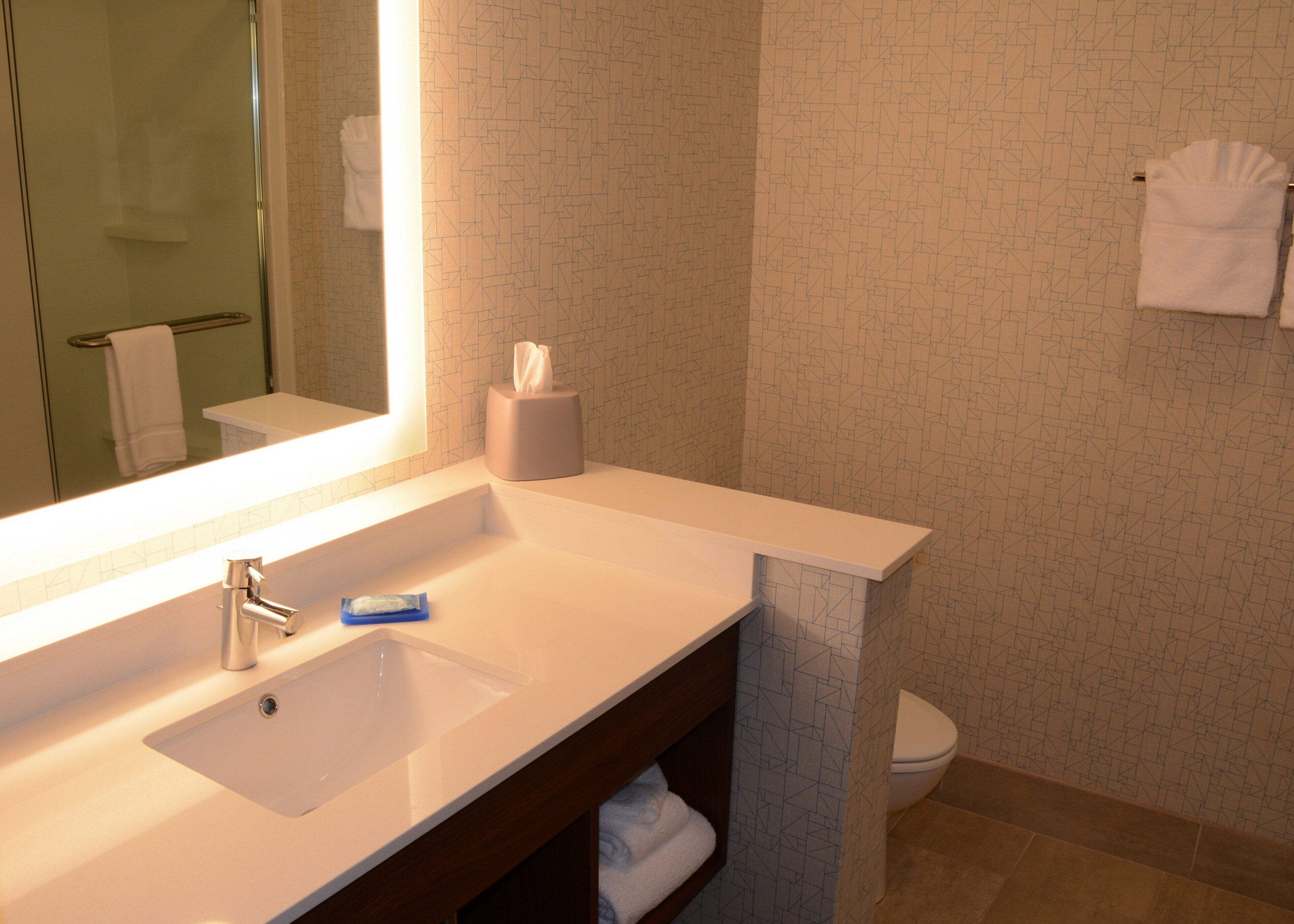 A bathroom with a white sink, a mirror, a towel rack, and a toilet.