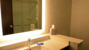 A bathroom with a large mirror, a sink, a towel rack, and a toilet.
