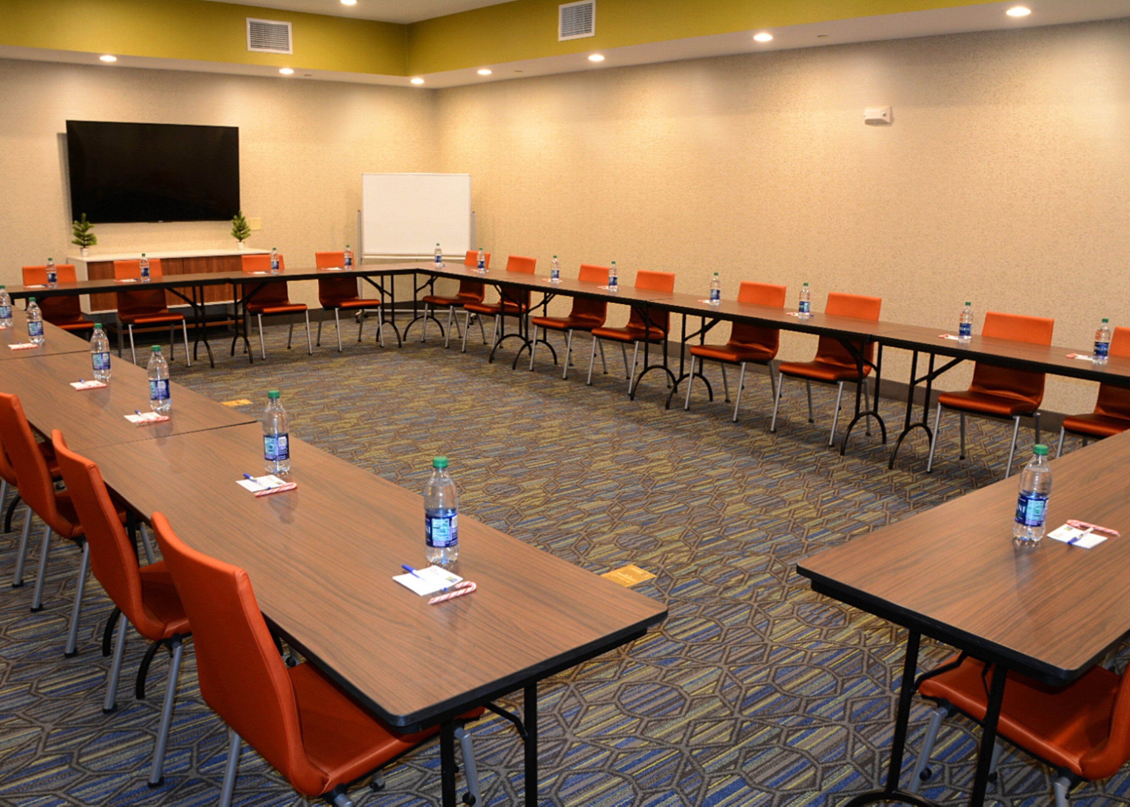 A conference room with a long table, multiple chairs, water bottles, and a whiteboard.