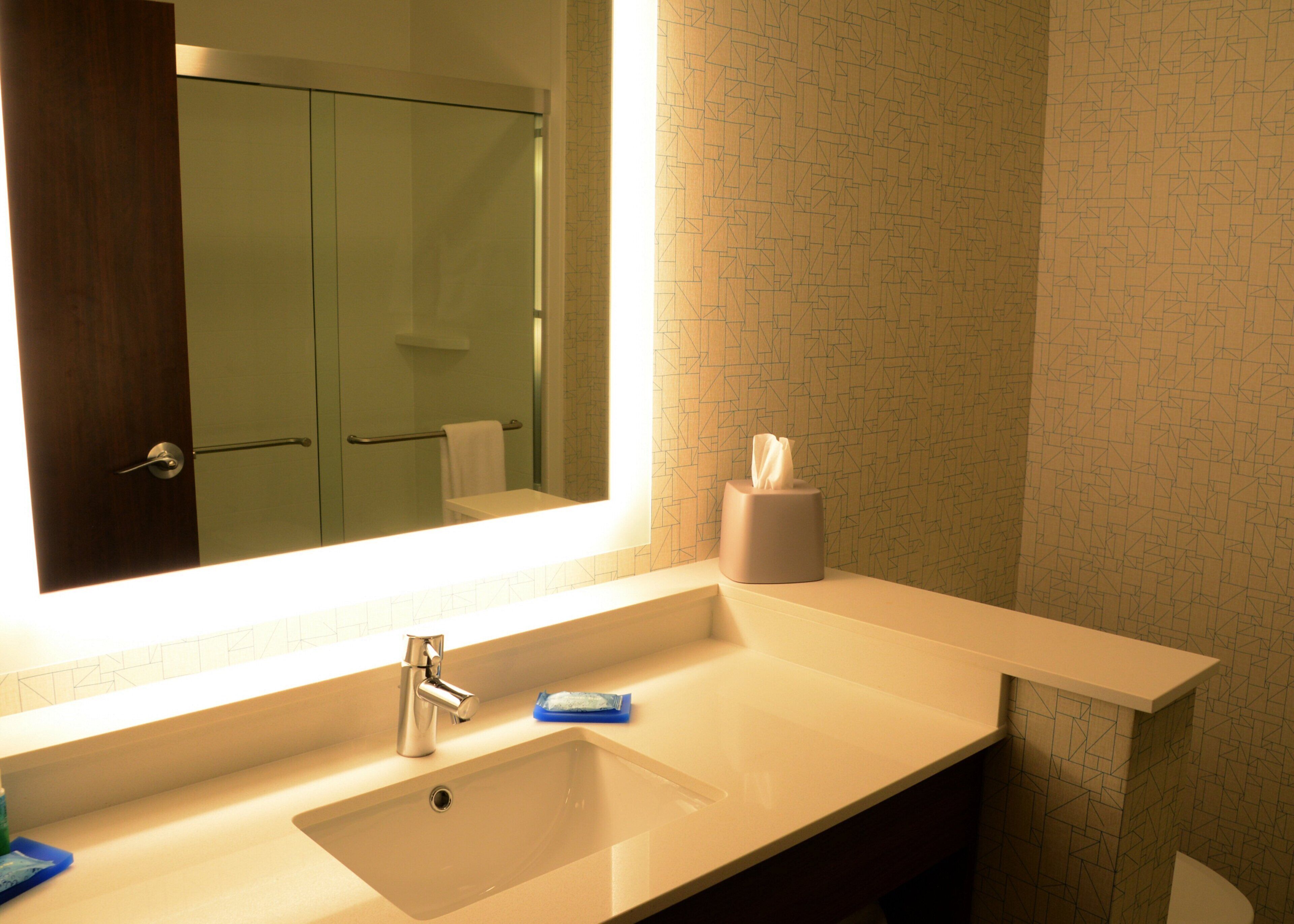 A bathroom with a large mirror, a sink, a towel rack, and a toilet.