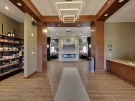 A hotel lobby with a reception desk, a fireplace, and shelves stocked with snacks.