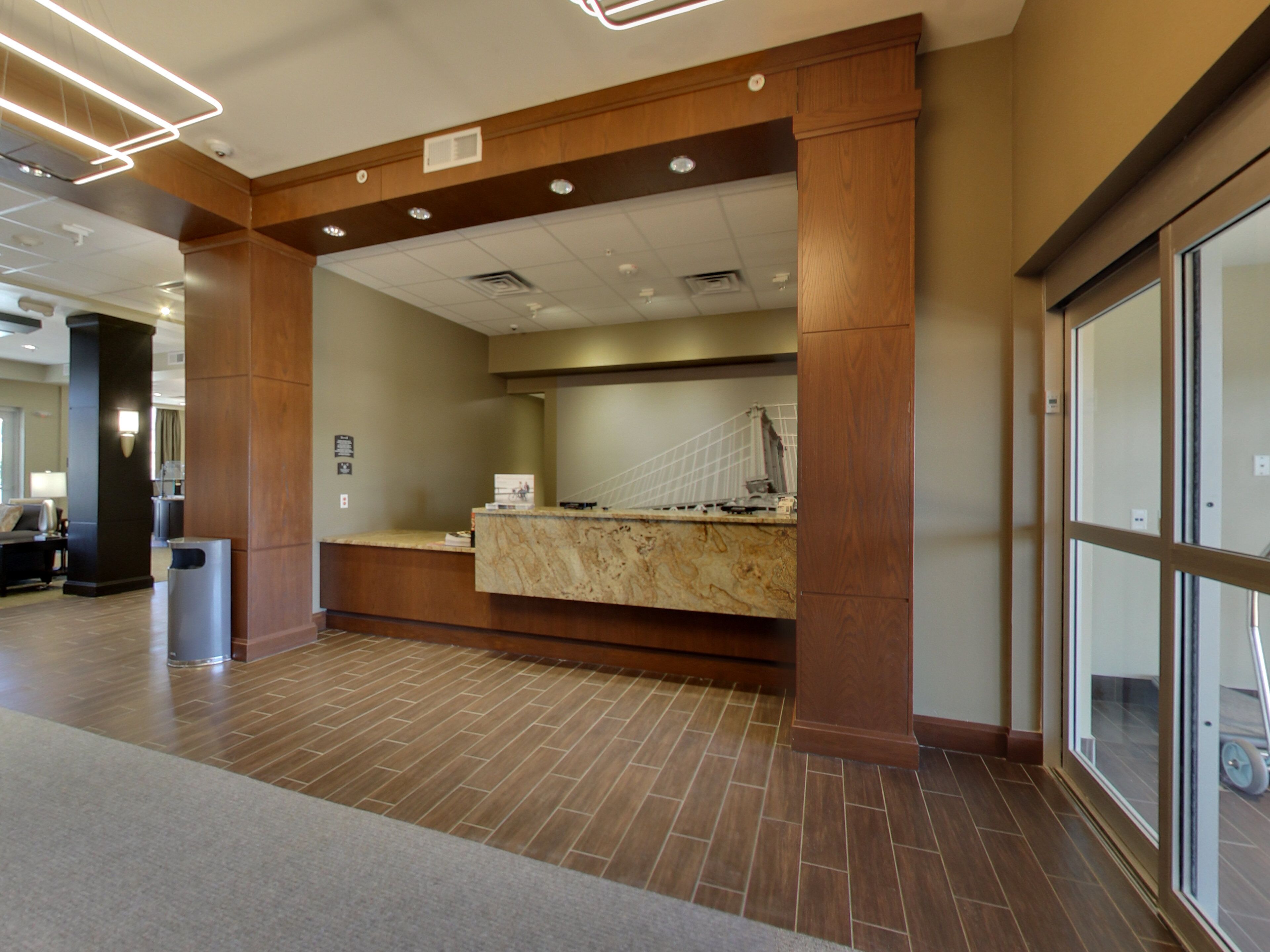 A reception area with a marble counter, wooden pillars, and a tiled floor.