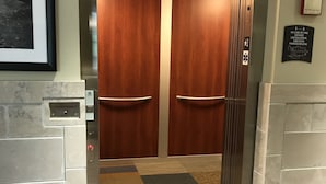 Un ascensor con puertas de madera y una pared de mármol.