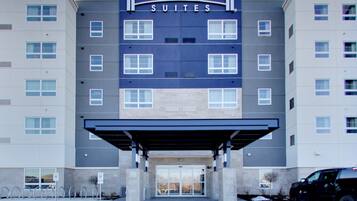 A Staybridge Suites hotel building with a covered entrance, multiple windows, and a parking area.