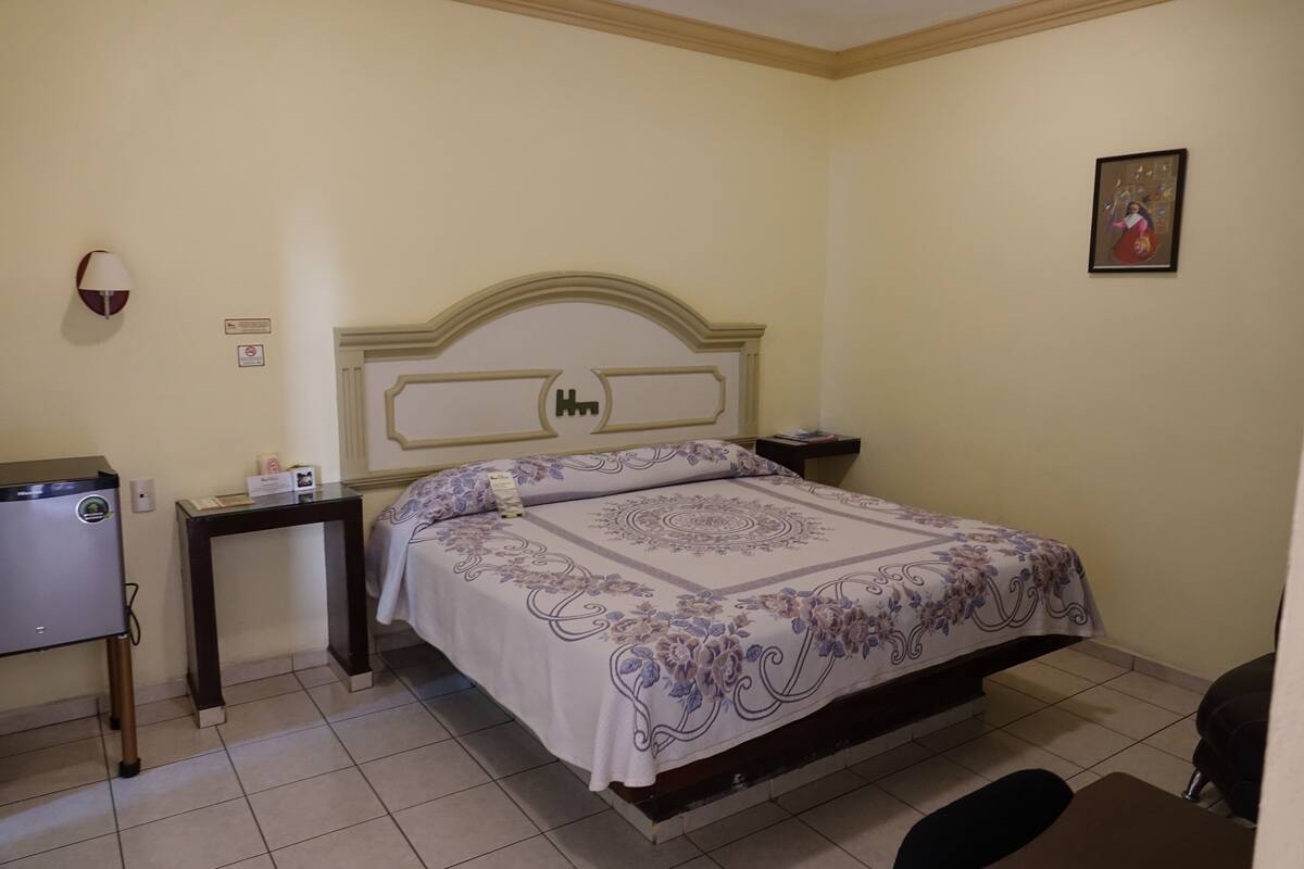 A bedroom with a bed, bedside tables, a lamp, and a small desk.