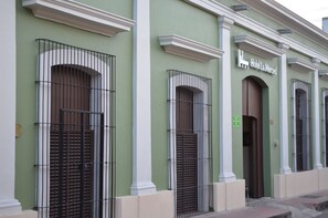 A hotel facade with green walls, white trim, and barred windows.