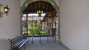 An arched entrance with wrought iron gates, a bench, and a view of a garden. - La Merced Hotel (Colima)