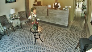 A reception area with a wooden reception desk, a clock, a TV, and a floral arrangement. - La Merced Hotel (Colima)