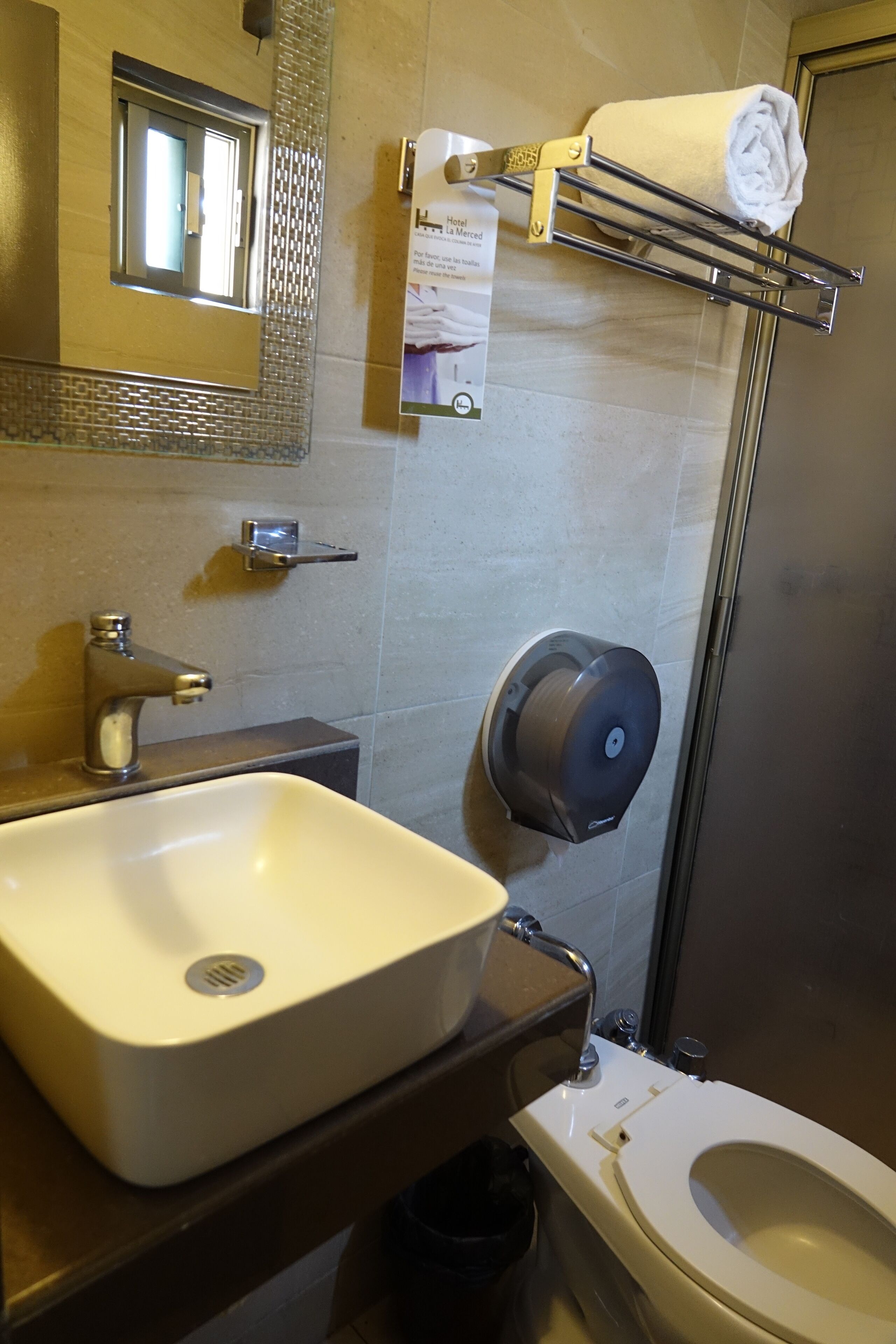 Un baño con lavamanos, inodoro, toallero y secador de manos.