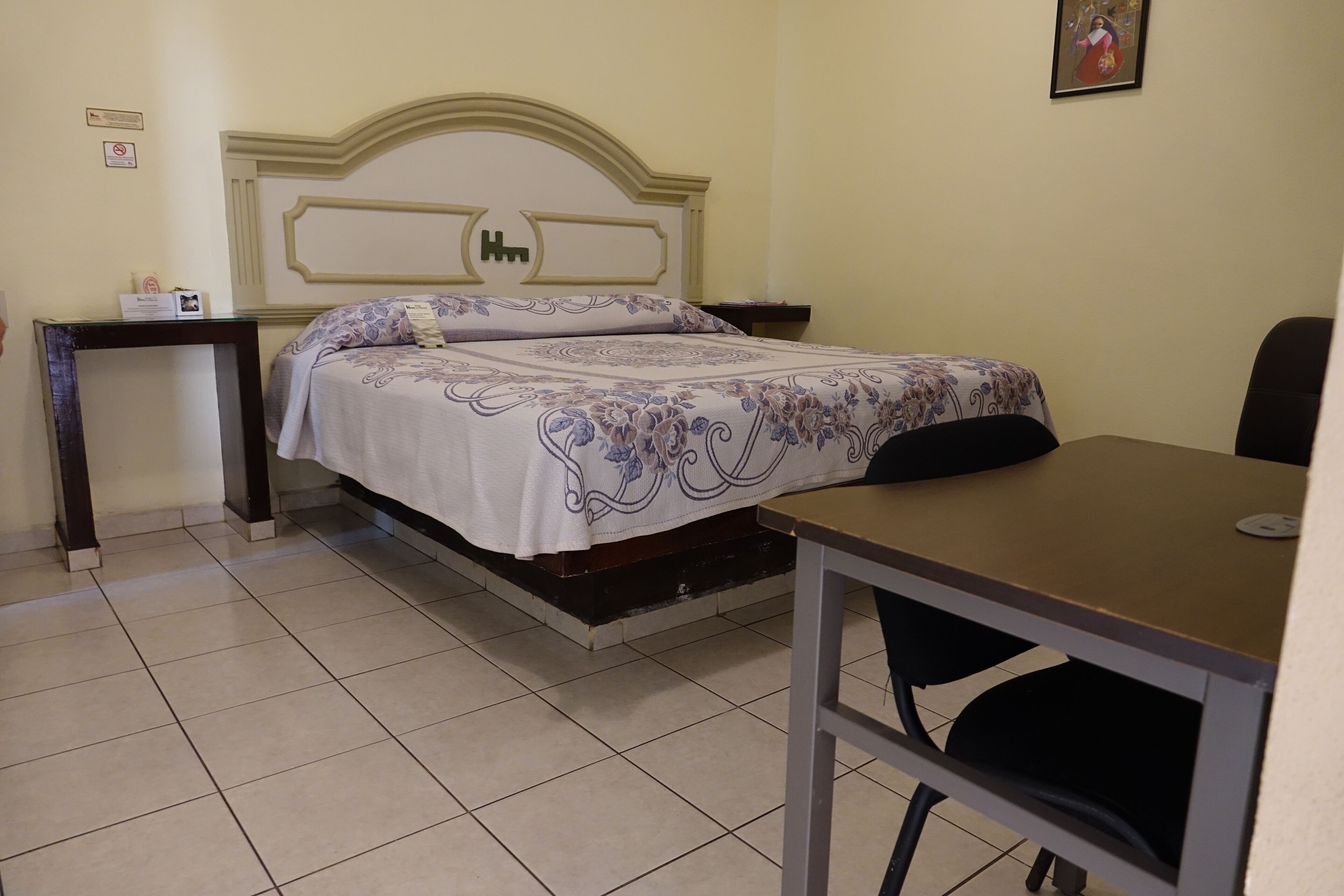 A hotel room with a bed, a desk, and a chair.