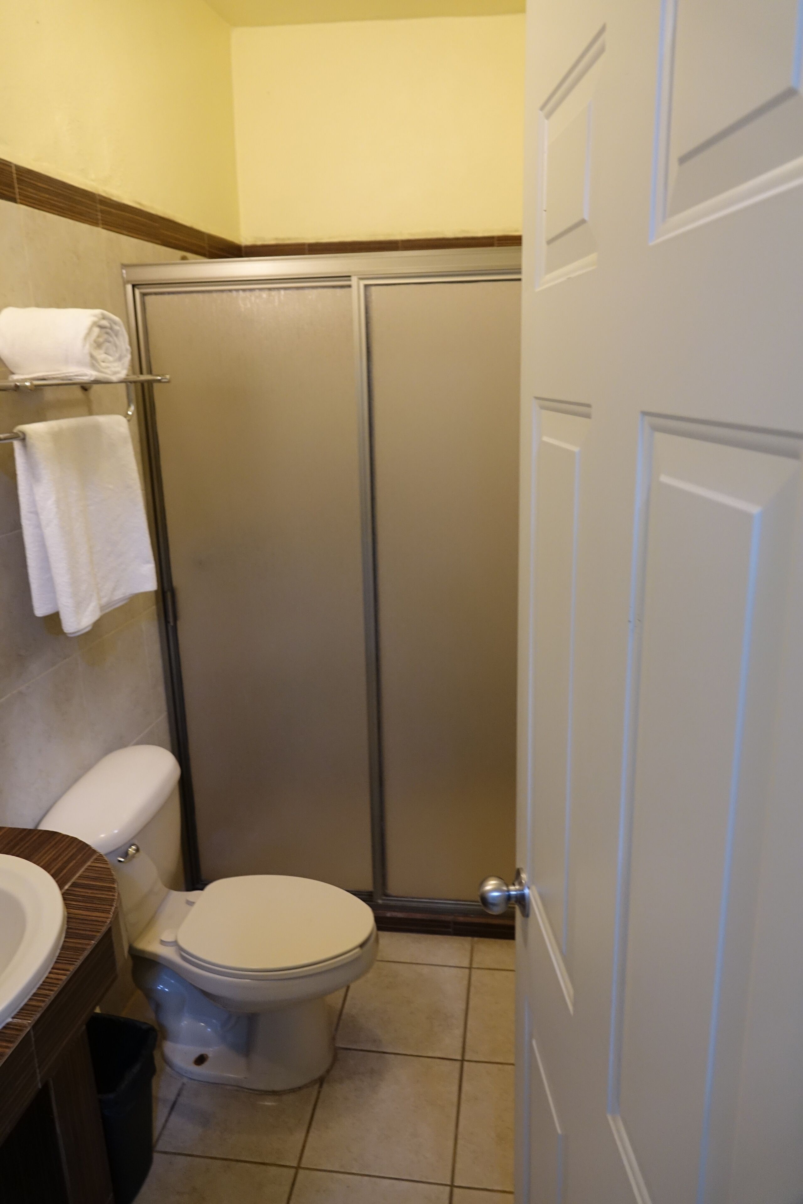 A bathroom with a toilet, a shower enclosure, and a towel rack.