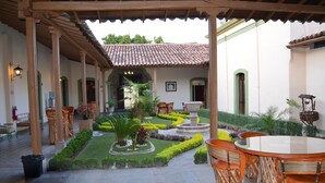 A courtyard with a pergola, seating area, and a fountain surrounded by well-maintained gardens. - La Merced Hotel (Colima)