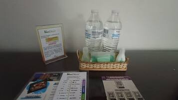 A table with a menu, a QR code for hotel services, and a basket containing water bottles and a green bottle.