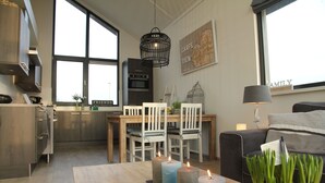 Una cocina moderna con comedor, ventanas amplias y un rincón de descanso acogedor con lámpara.