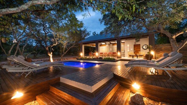 Un área de piscina moderna al aire libre con sillones de descanso, un jacuzzi y una terraza de madera.
