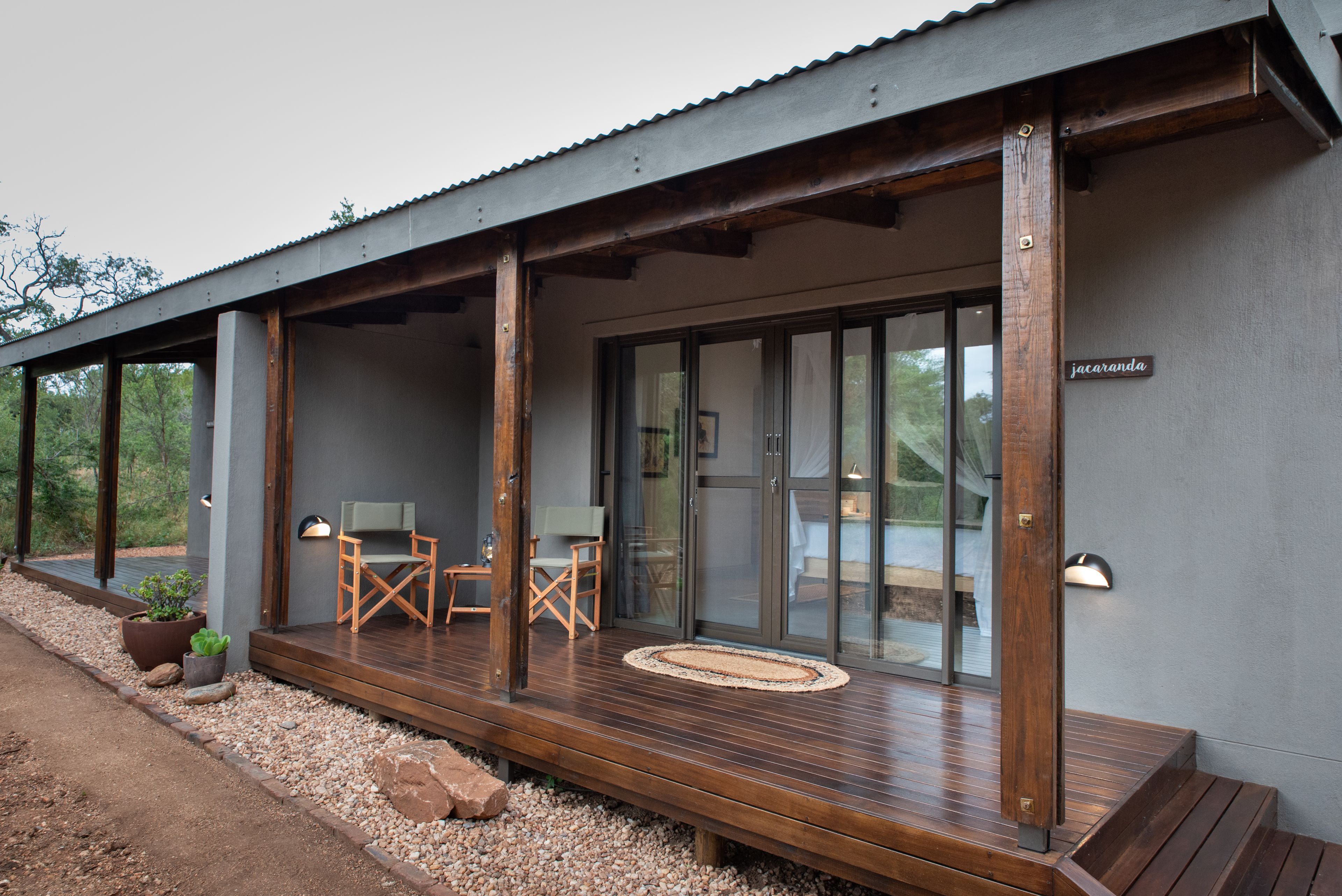 Een modern gebouw met een houten terras, een zitgedeelte en een bord waarop 
