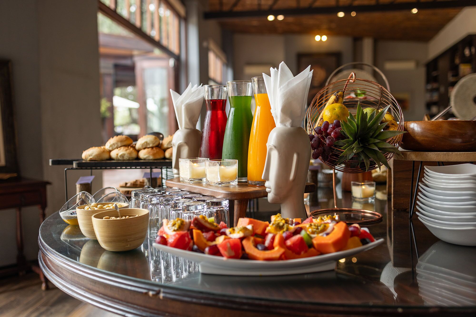 A breakfast buffet with various food items, drinks, and a fruit basket.