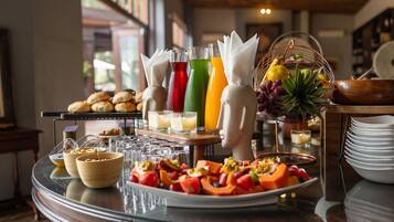 A breakfast buffet with various food items, drinks, and a fruit basket.