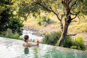Una piscina al aire libre, sillones reclinables de piscina