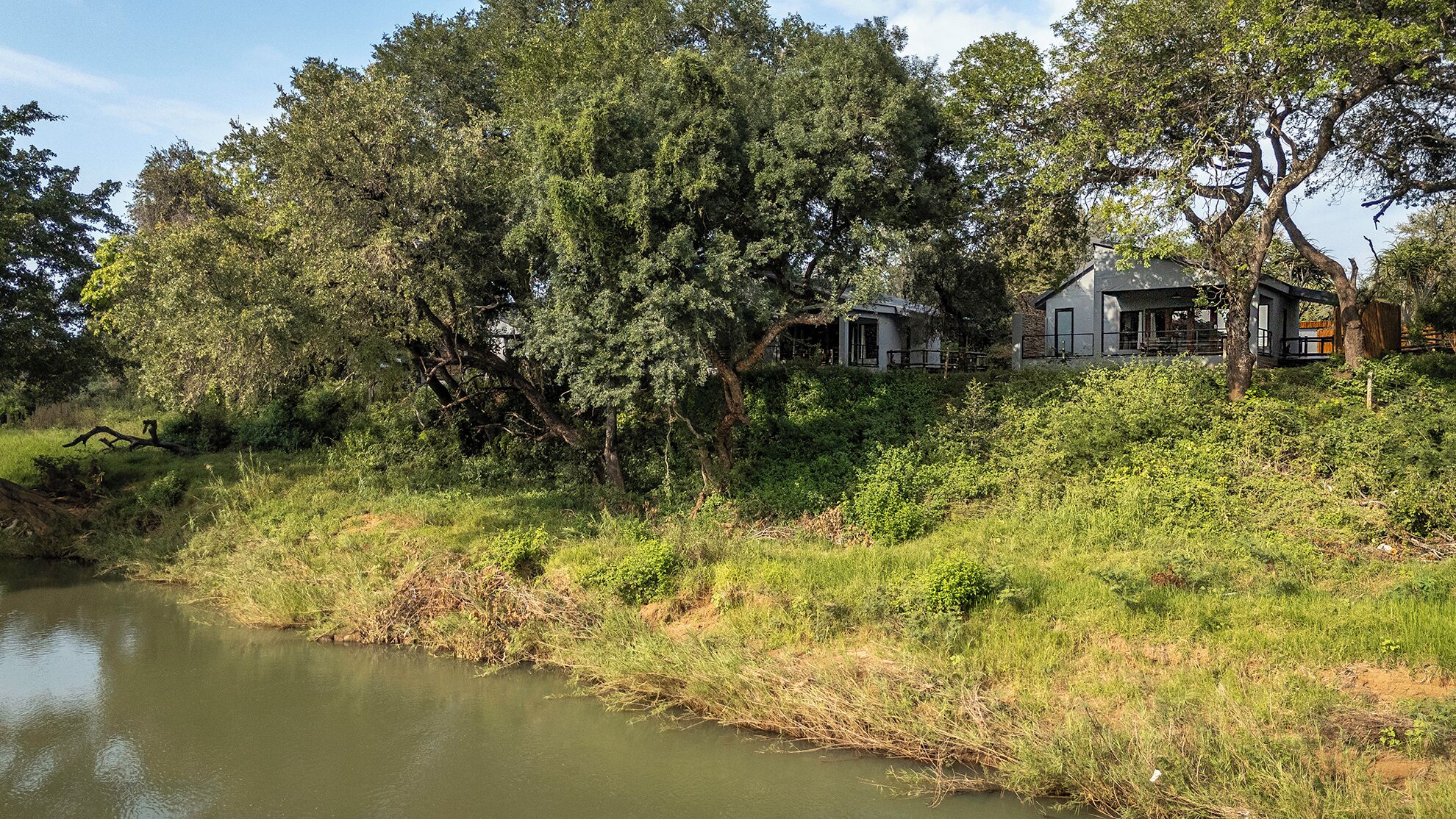 Uma propriedade à beira do rio, com uma casa, cercada por árvores e vegetação densa.