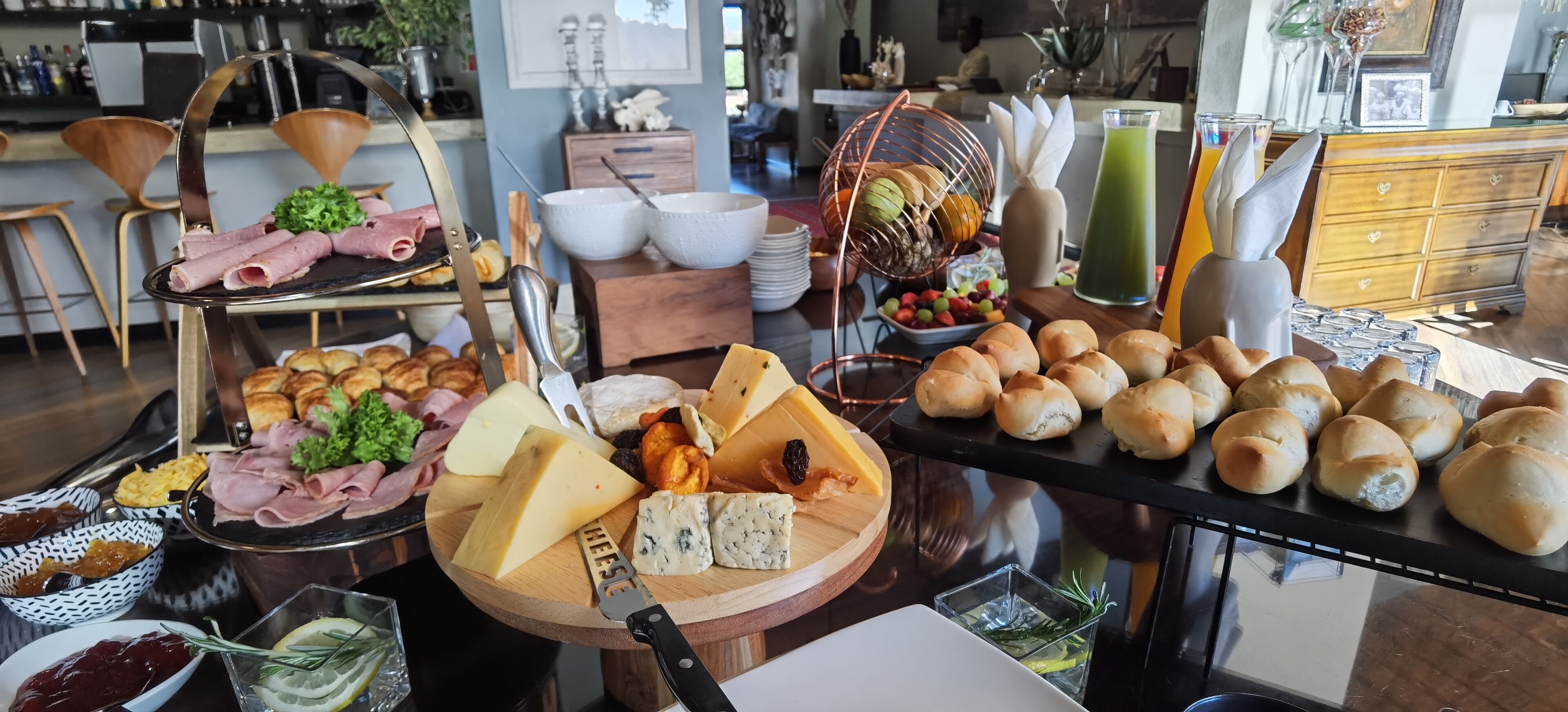 A buffet with various cheeses, meats, and pastries.
