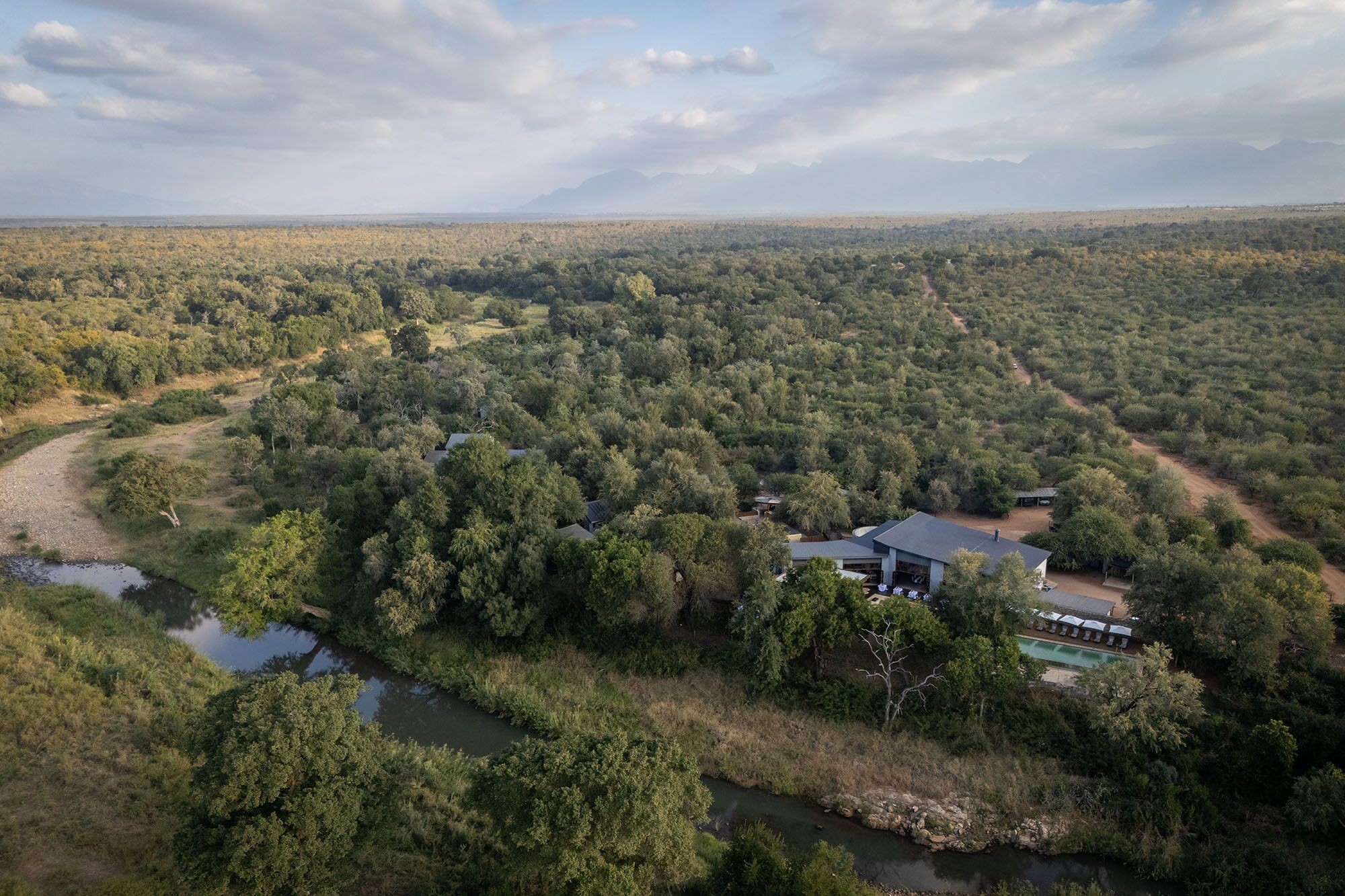 Abgelegenes, bewaldetes Gebiet mit einem kleinen Gebäude, das einen Pool und Sitzgelegenheiten im Freien bietet.