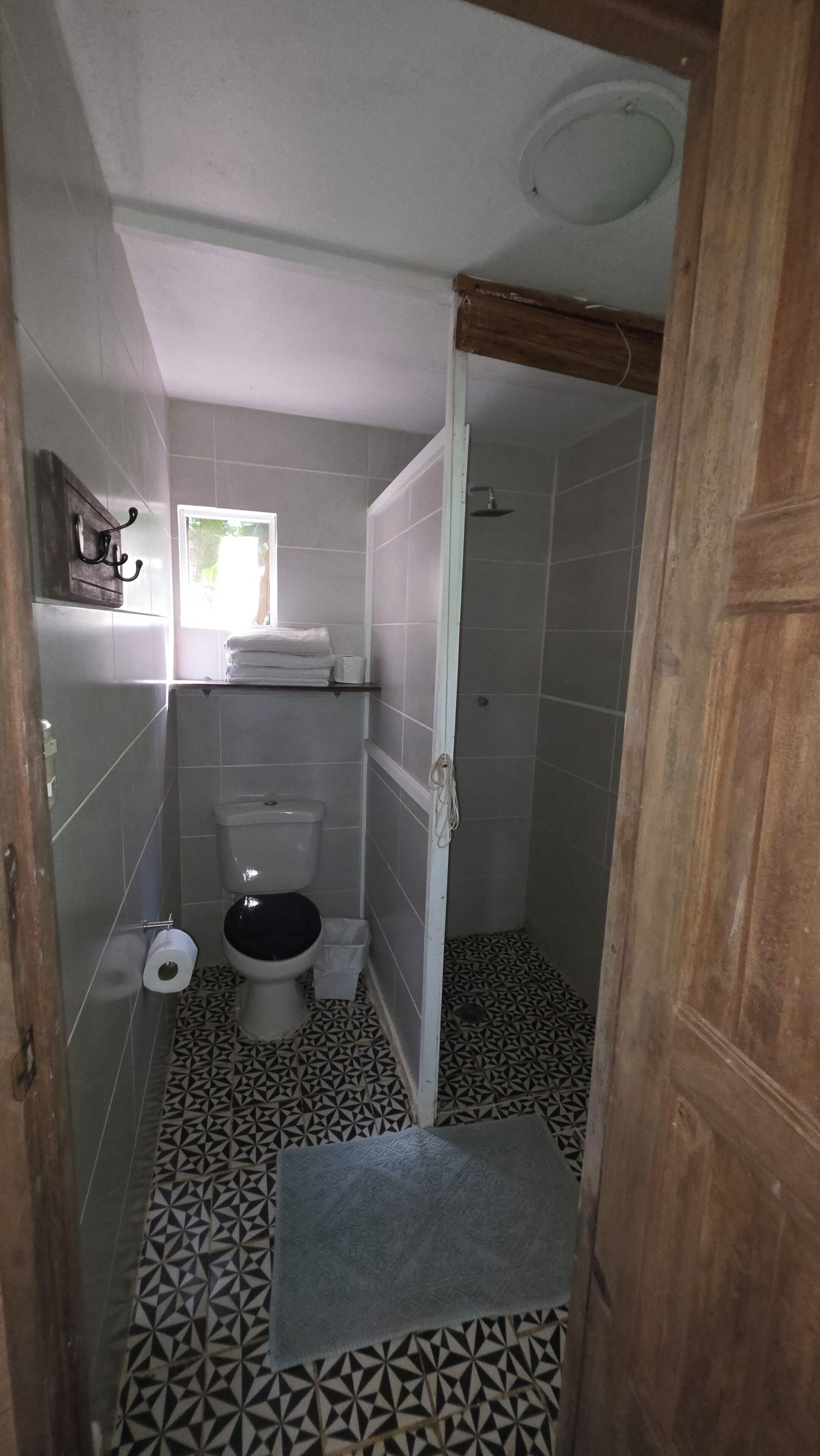 A small, compact bathroom with a toilet, a sink, and a shower area.