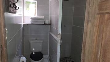 A small, compact bathroom with a toilet, a sink, and a shower area.