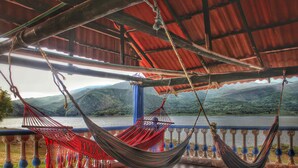 A hammock under a metal roof overlooking a lake with mountains in the background. - Marineros Club Nautico (Prado)