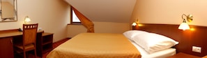 A bedroom with a bed, bedside table, lamp, and a mirror.