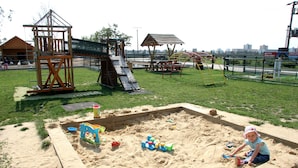 A playground with sand play area, wooden structures, and a slide. - Hotel Rozálka (Pezinok)