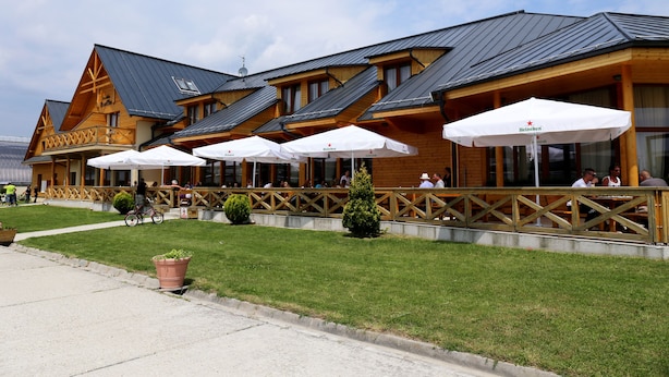 A wooden lodge with outdoor seating and umbrellas. - Hotel Rozálka (Pezinok)
