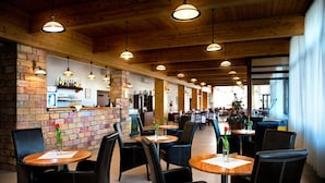 A restaurant with wooden ceilings, brick walls, and multiple tables with chairs. - Hotel Rozálka (Pezinok)