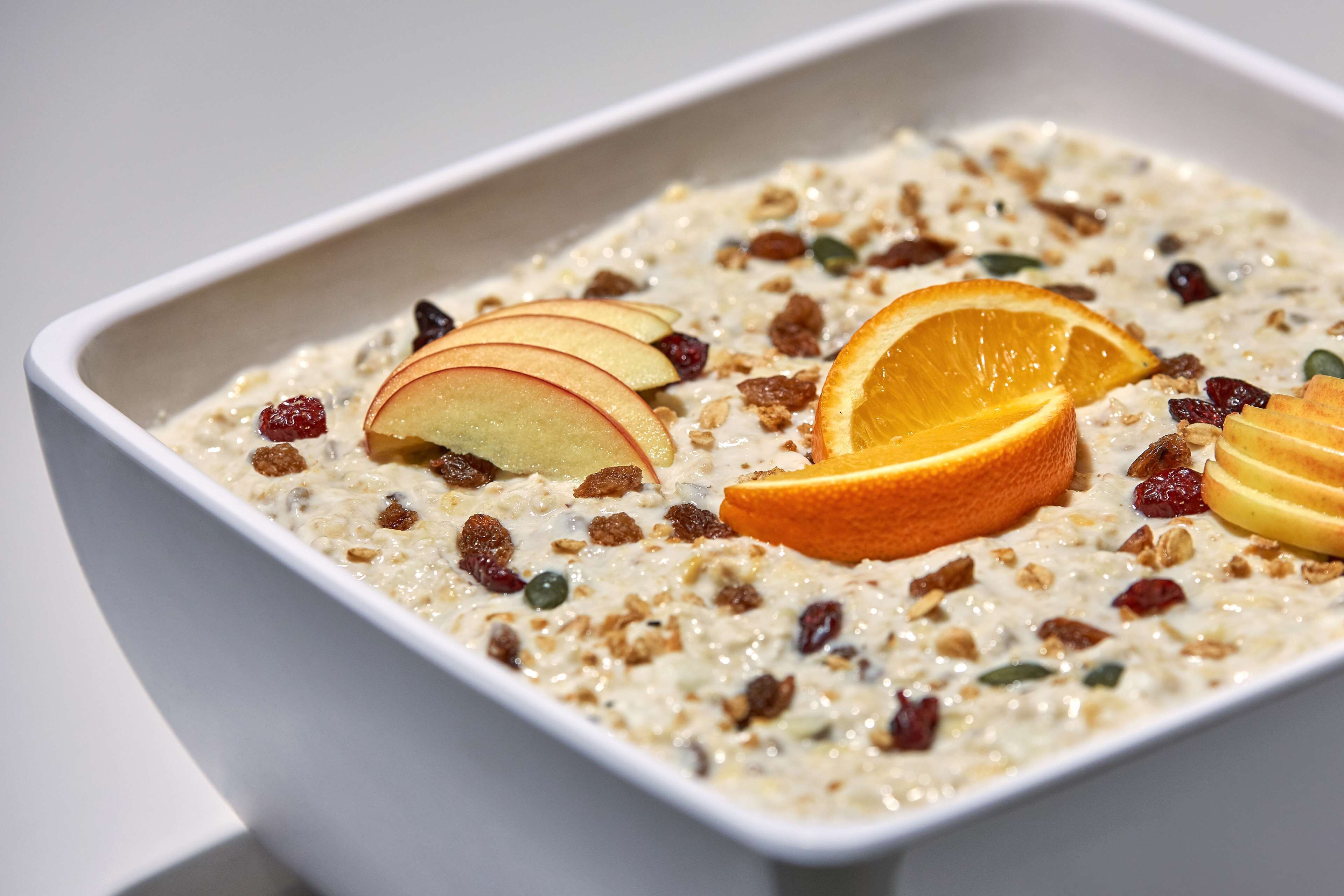Un tazón de avena con rodajas de manzana y naranja.
