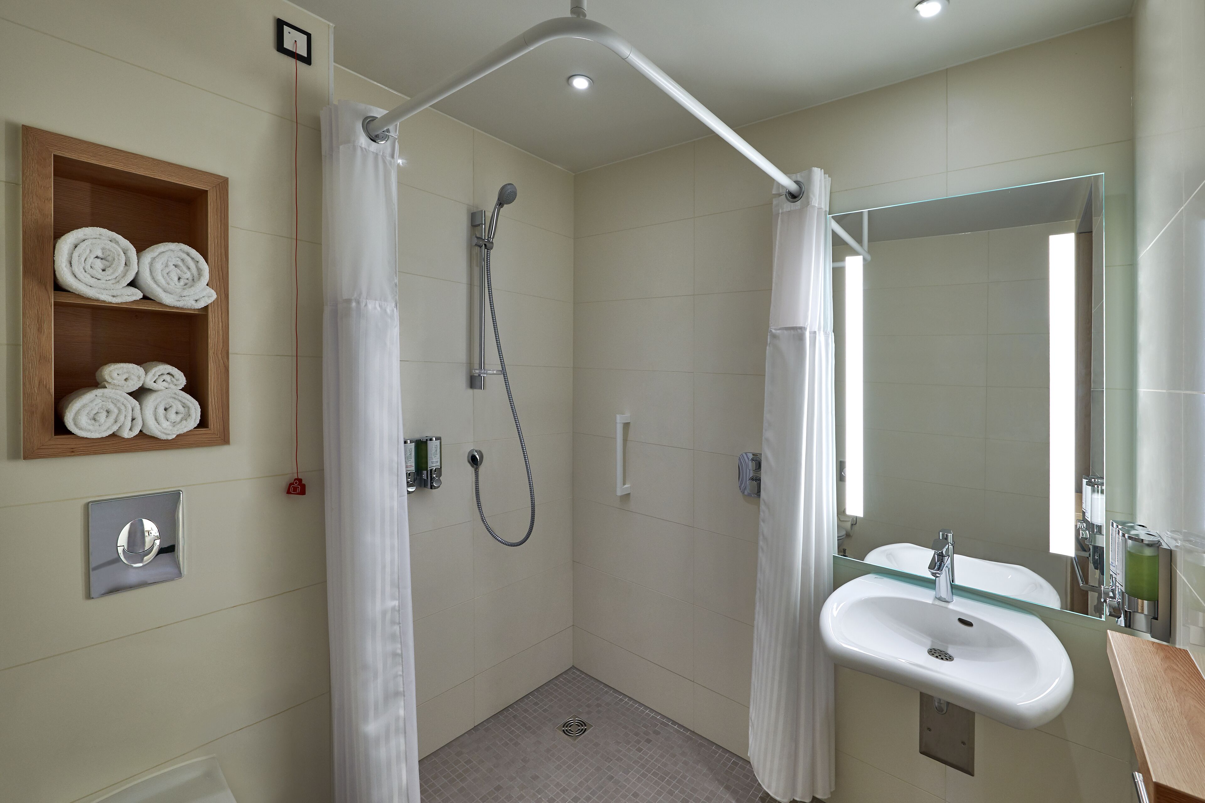 Un baño moderno con cabina de ducha de vidrio, un estante de madera para toallas, un lavabo y un espejo grande.