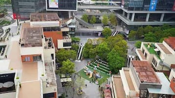 Un edificio de varios pisos con un jardín en la azotea, un espacio al aire libre techado con asientos y una fuente visible.
