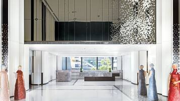 A spacious lobby with a high ceiling, a seating area, and a view of the cityscape.