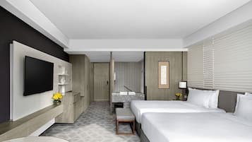 A modern hotel room with a large bed, a flat-screen TV, a desk, and a bathroom visible through an open door.