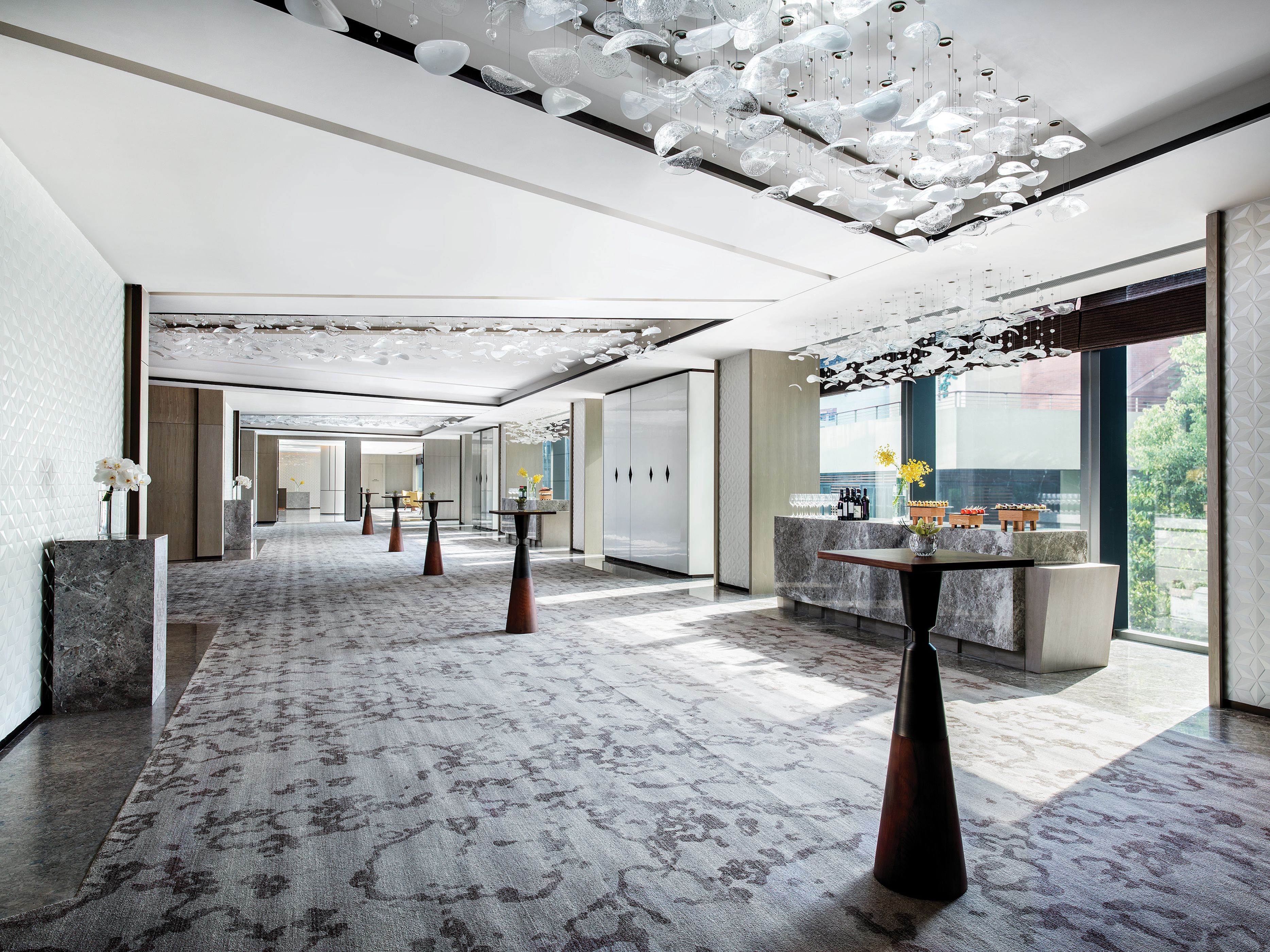 Un amplio vestíbulo de hotel con piso de mármol, mobiliario moderno y un techo decorativo.
