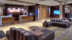 A modern hotel lobby with a reception desk, seating area, and a television screen displaying a map. - Courtyard by Marriott St. Louis Chesterfield (Chesterfield)