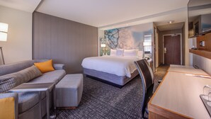 A hotel room with a bed, a sofa, a desk, and a chair. - Courtyard by Marriott St. Louis Chesterfield (Chesterfield)