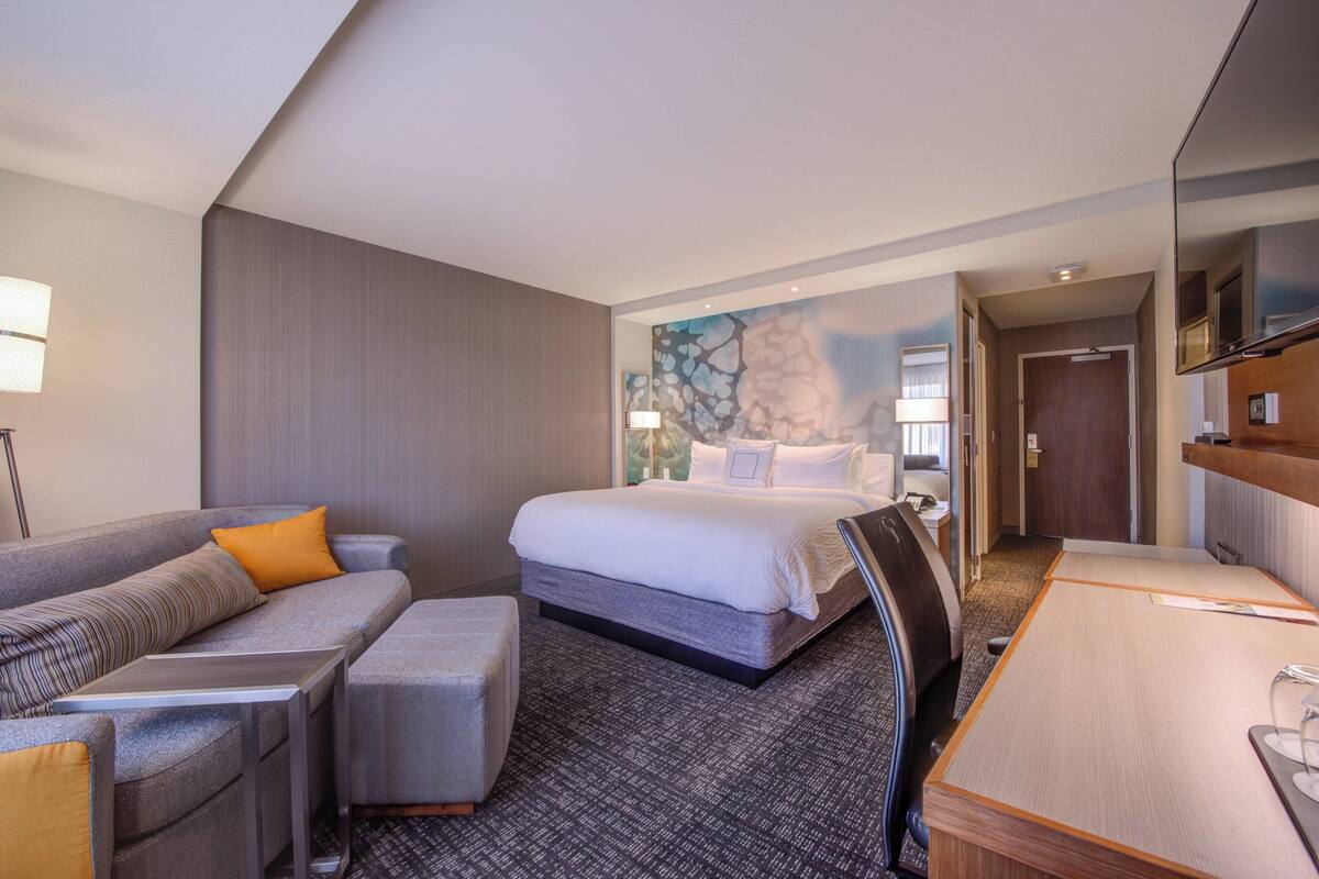 A hotel room with a bed, a sofa, a desk, and a chair.