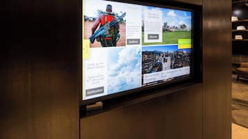 A digital display with news and weather updates, including headlines about Colombia's FARC rebels and a weather forecast for 87°F and partly cloudy.