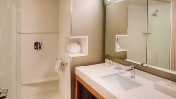 A modern bathroom with a glass shower enclosure, a white sink with a mirror, and a towel rack.