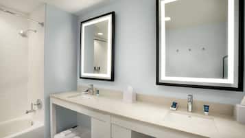 A modern bathroom with two sinks, a bathtub, and a large mirror.