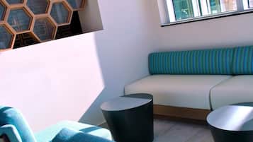 A modern lounge area with a sofa, two armchairs, and a round table.