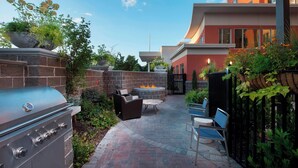 Ein Patio-Bereich mit Grill, Sitzgelegenheiten und einer Feuerstelle.