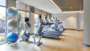 Ein Fitnessstudio mit Trainingsgeräten, großen Fenstern und Blick ins Freie.