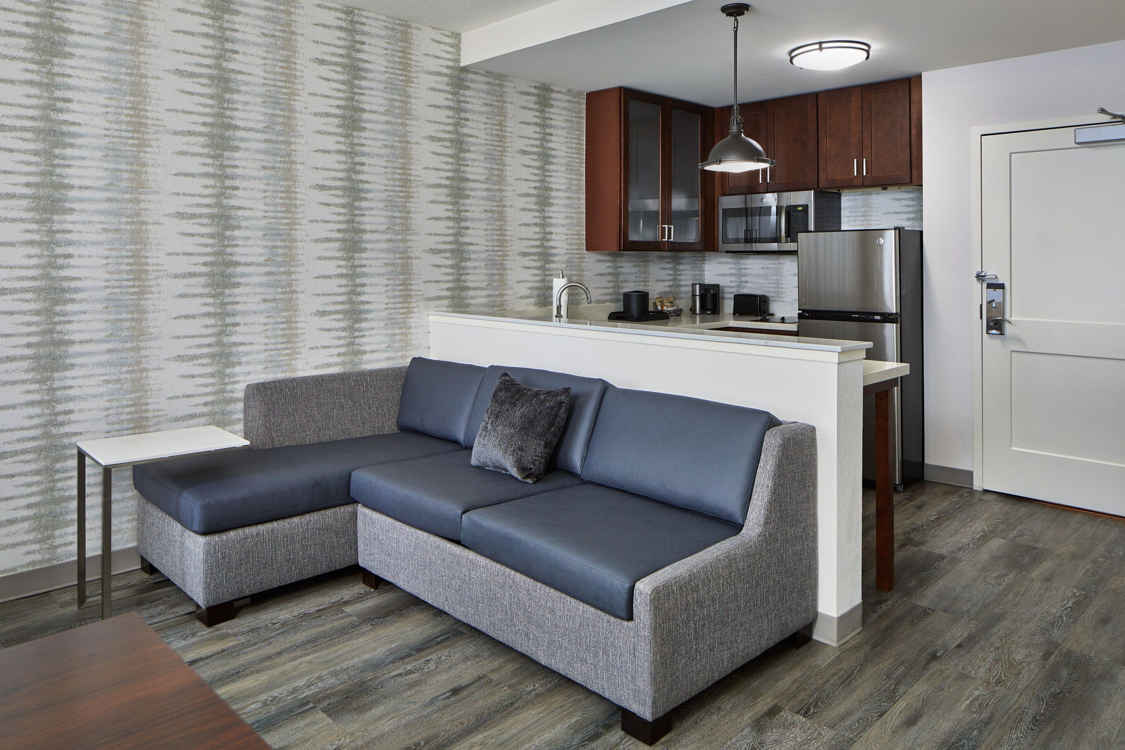 A modern living room with a gray sectional sofa, a small white side table, and a dark wooden coffee table.